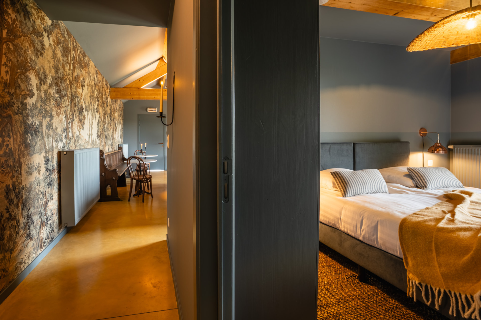 Slaapkamer na: bed met velours hoofdbord, gestreepte kussens, okergele plaid en koperen wandlamp