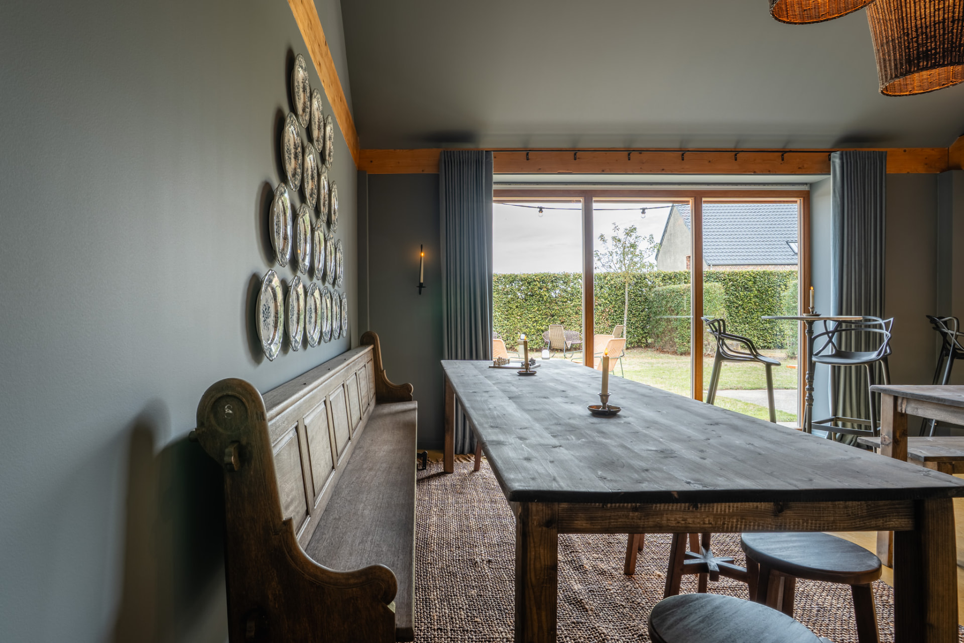 Groepsruimte na: massief houten lange tafel, oude kerkbank en een wand met blauw-wit borden